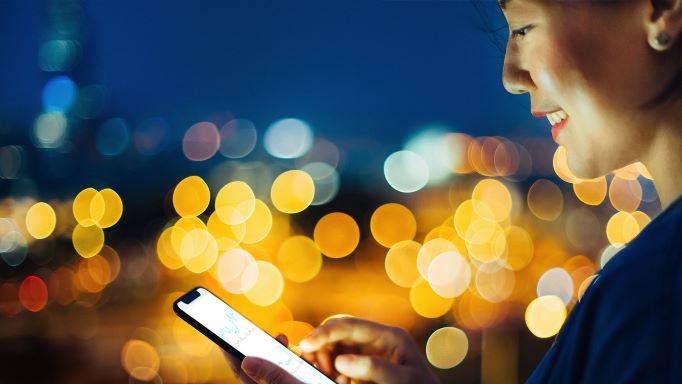 Woman on phone with city lights in the background